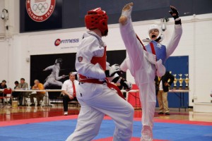 Ivan Smirnou, blue, performs an axe kick against his opponent at the National Collegiate Taekwondo Championship on Sunday April 14 in Colorado Springs.  Photo by Courtland Wilson.